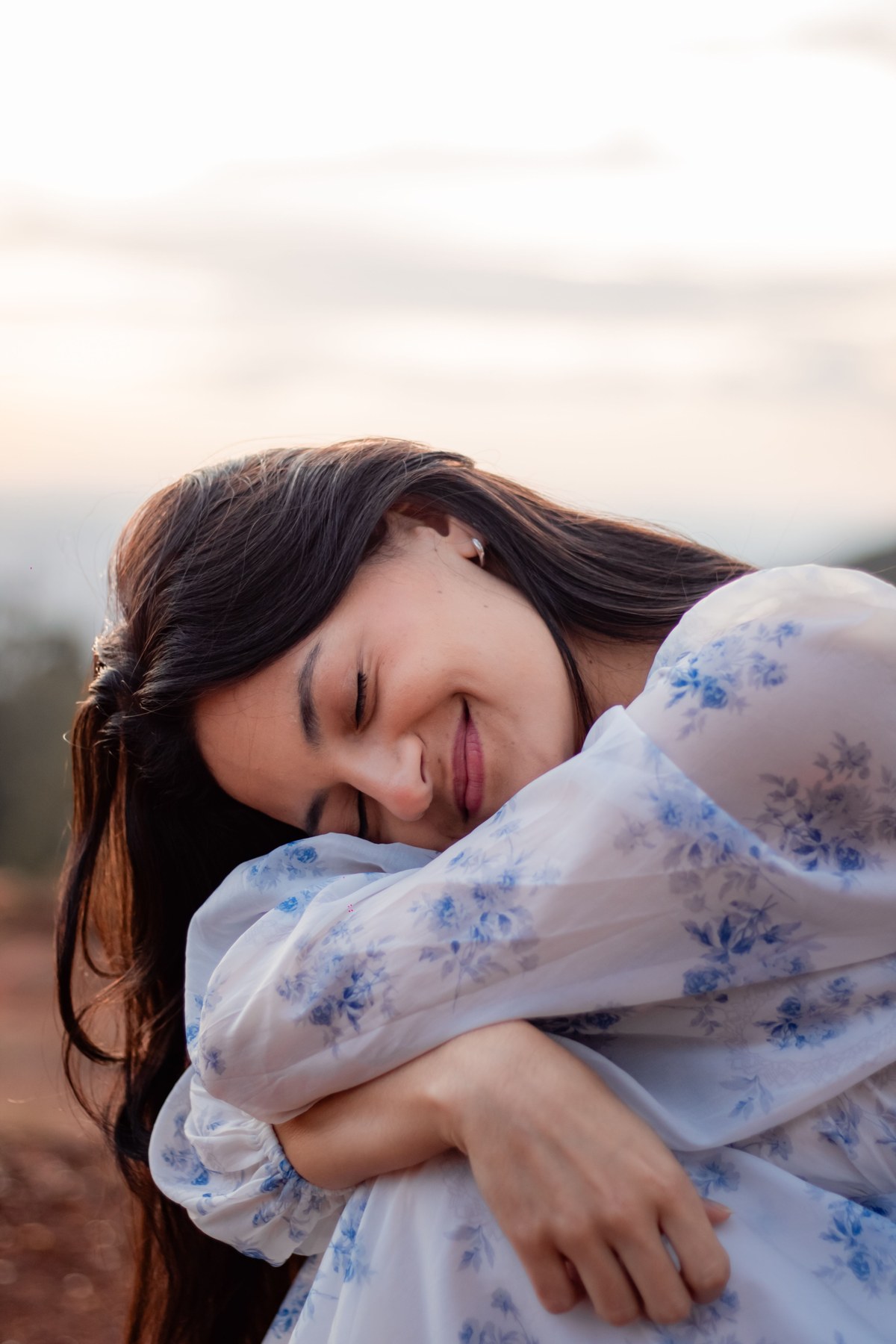 A woman resting her head on her arms with a quiet smile